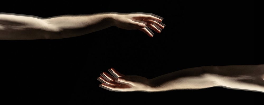 Christopher Matthews - Act 3 A black background with two arms reaching towards the centre. They have pale skin and relaxed hands.