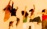 FREE - Toussiant to Move © Solomon Charles-Kelly Five people are mid-jump against a plain background, wearing casual colorful clothing and displaying energetic body language.