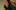 A dancer with long hair and a green shirt smiling, raising one arm. The image is intentionally grainy and cropped to not see her whole face.